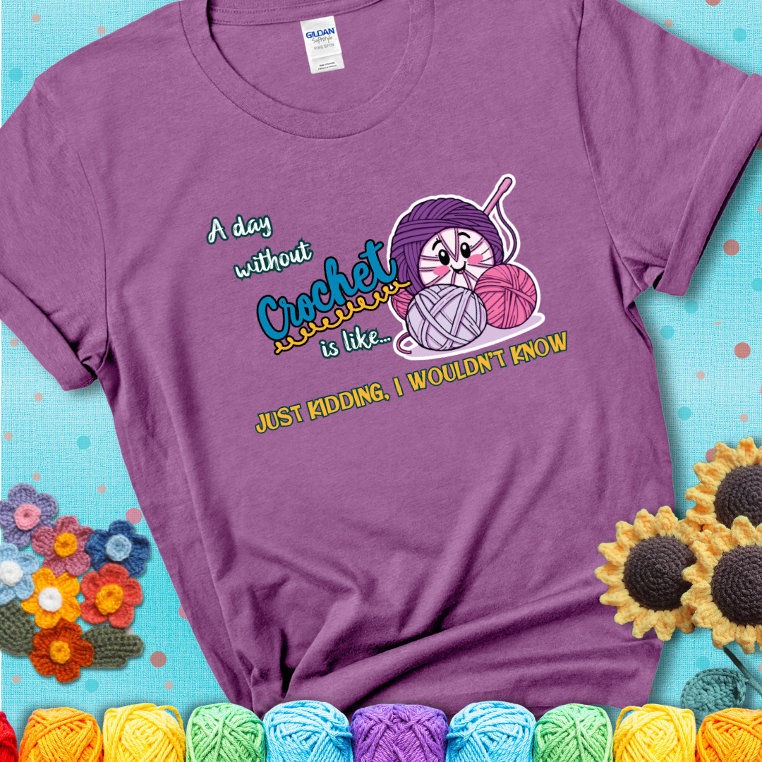 Light purple t-shirt showing a smiling yarn ball character with text “A day without crochet is like... just kidding, I wouldn’t know”; funny crochet t-shirt.