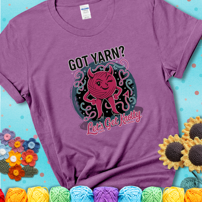 Heather Radiant Orchid t-shirt with a cheeky pink yarn ball wearing devil horns, arms, and legs, winking beneath the phrase “Got Yarn? Let’s Get Knotty
