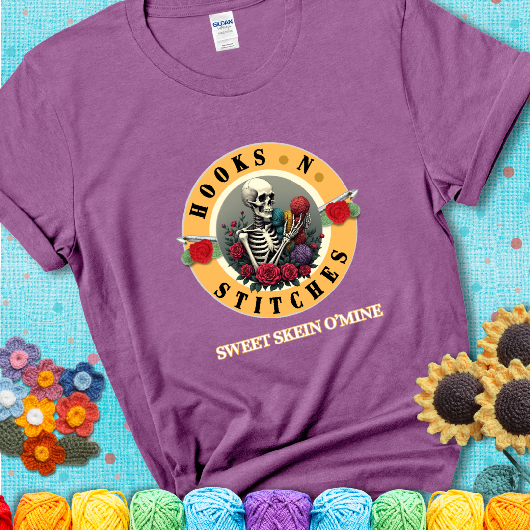 Heather Radiant Orchid t-shirt with a skeleton holding colorful yarn, roses, crochet hooks, and the phrases “Hooks ’N Stitches” and “Sweet Skein O’Mine.”