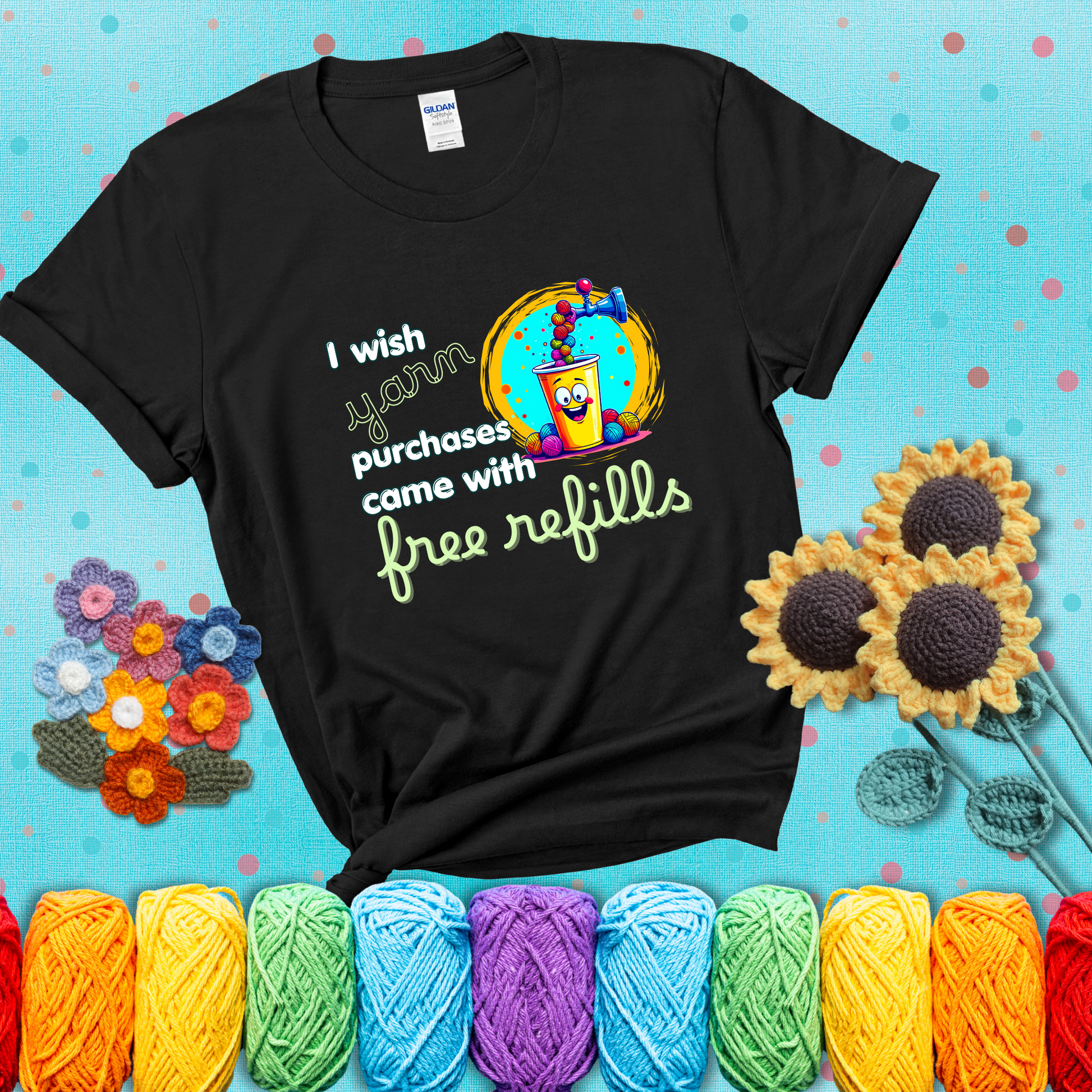 A bright yellow cup with a smiling face is being filled with colorful yarn balls from a soda machine, with the phrase “I wish yarn purchases came with free refills,” showing a black tee with a teal sunflower background