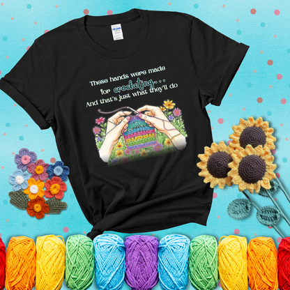 Illustration of two hands crocheting a rainbow swatch, surrounded by vibrant flowers with the phrase “These hands were made for crocheting… and that’s just what they’ll do,” showing a black tee with a teal sunflower background