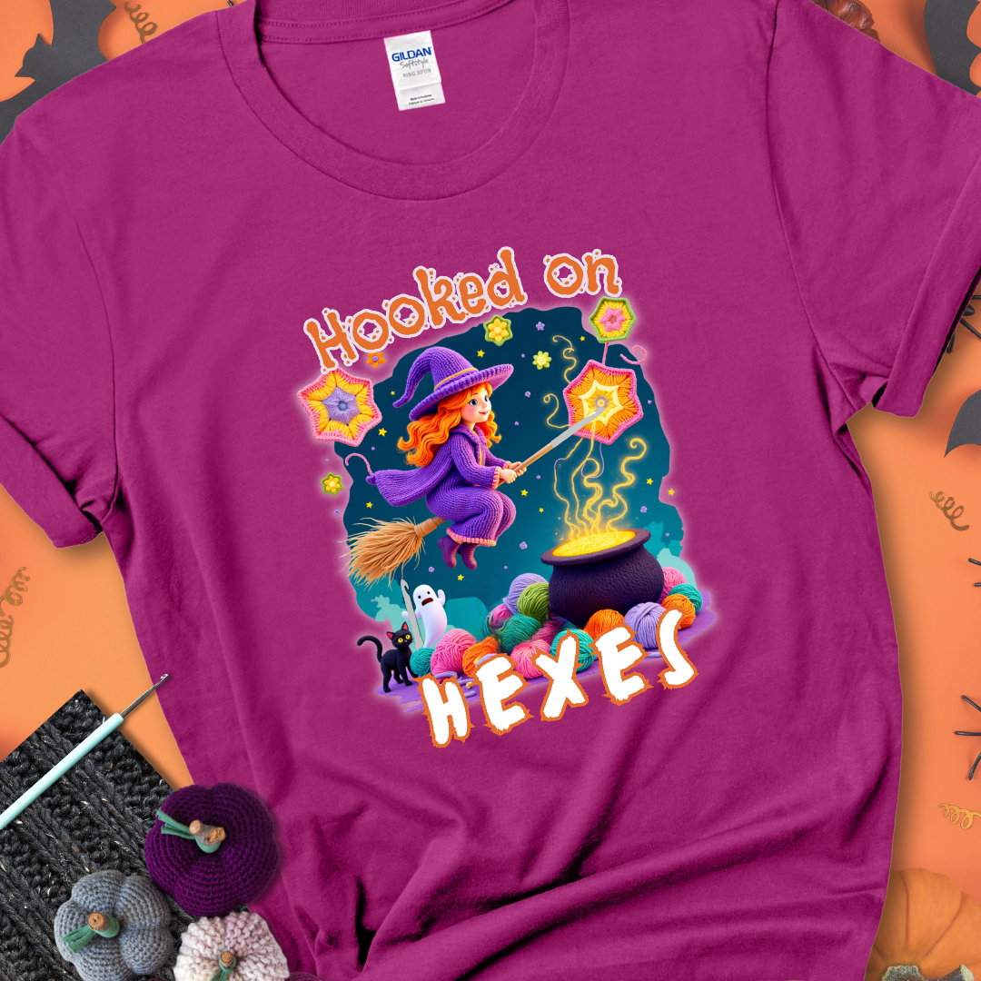 Antique Heliconia t-shirt with stars, hexagon motifs, and a crochet hook, with text reading “Hooked on Hexes.”