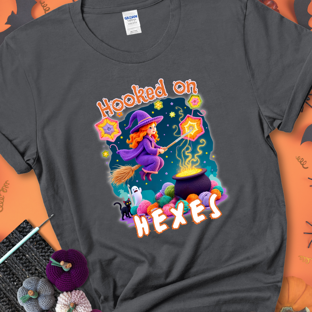 Charcoal t-shirt with stars, hexagon motifs, and a crochet hook, with text reading “Hooked on Hexes.”