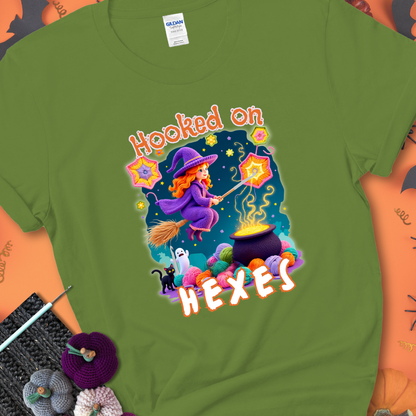 Kiwi t-shirt with stars, hexagon motifs, and a crochet hook, with text reading “Hooked on Hexes.”