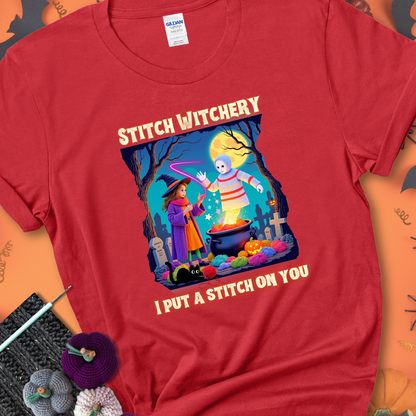Red t-shirt with a yarn witch casting a spell from a cauldron onto a floating crochet ghost, with text “Stitch Witchery” and “I Put a Stitch on You.”