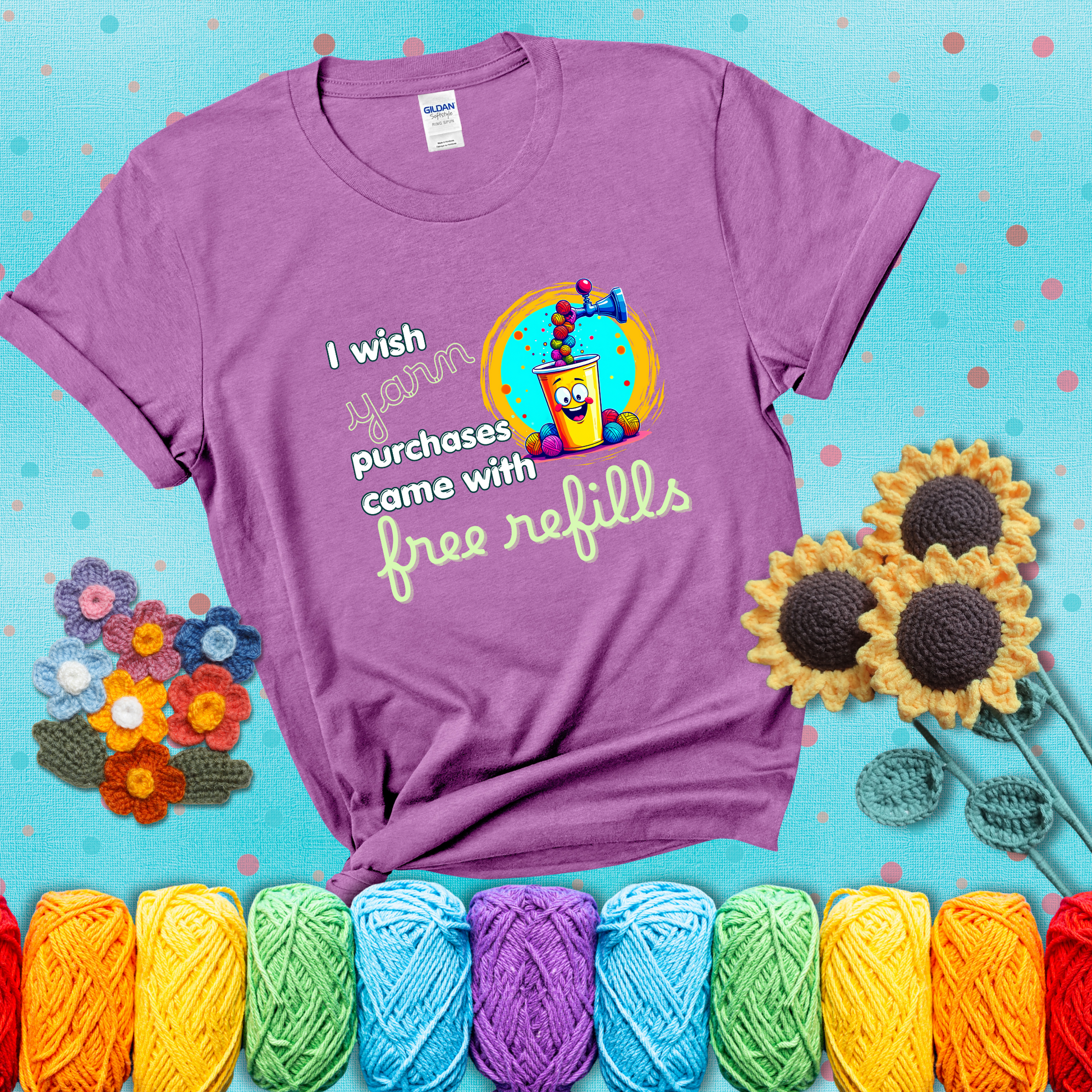A bright yellow cup with a smiling face is being filled with colorful yarn balls from a soda machine, with the phrase “I wish yarn purchases came with free refills,” showing a light purple tee with a teal sunflower background