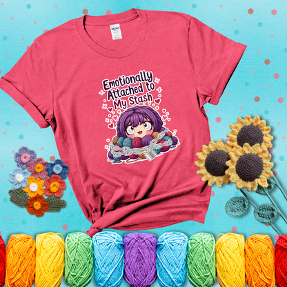 Rows of colorful yarn skeins stacked with playful text. Text reads: “Emotionally Attached to My Stash.” A humorous shirt for fiber lovers with growing collections, showing a light red tee with a teal sunflower background