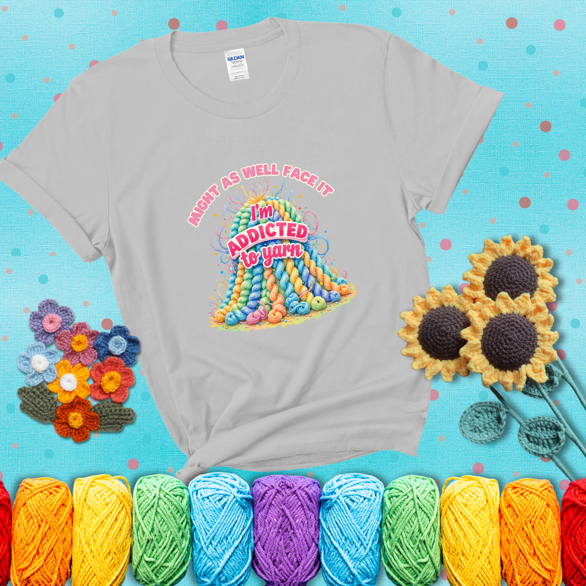 Colorful mountain of pastel yarn hanks with the phrase “Might as well face it, I’m addicted to yarn” in playful pink and red lettering showing a light grey tee with a teal sunflower background