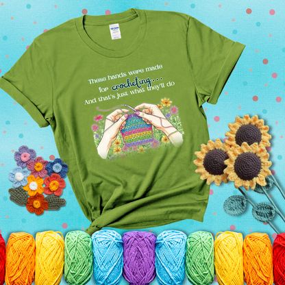 Illustration of two hands crocheting a rainbow swatch, surrounded by vibrant flowers with the phrase “These hands were made for crocheting… and that’s just what they’ll do,” showing a bright green tee with a teal sunflower background