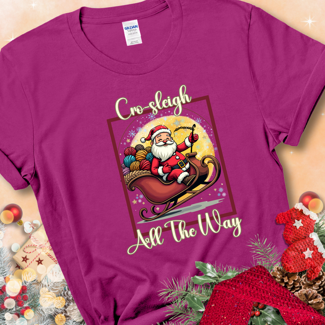 Antique Heliconia t-shirt with Santa riding in a sleigh overflowing with colorful yarn and the phrase “Cro-Sleigh All The Way.”