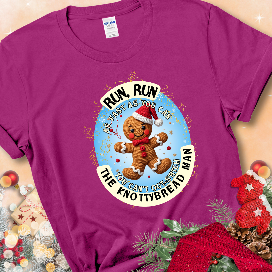 Antique Heliconia e t-shirt with a crocheted gingerbread man in a Santa hat and the phrase “You Can’t Out-Stitch the Knottybread Man.”