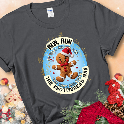 Charcoal t-shirt with a crocheted gingerbread man in a Santa hat and the phrase “You Can’t Out-Stitch the Knottybread Man.”