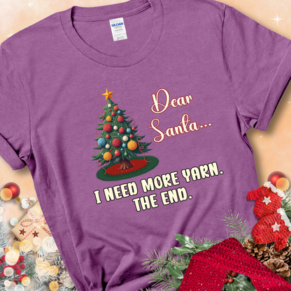 Heather Radiant Orchid t-shirt with a Christmas tree decorated with yarn-ball ornaments and the stitched message “Dear Santa… I Need More Yarn. The End.”