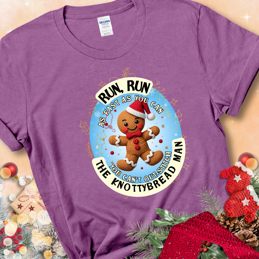 Heather Radiant Orchid t-shirt with a crocheted gingerbread man in a Santa hat and the phrase “You Can’t Out-Stitch the Knottybread Man.”