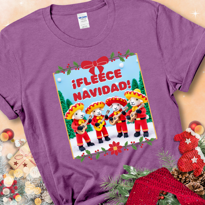 Heather Radiant Orchid t-shirt with four crocheted sheep in red mariachi outfits holding guitars, standing in a snowy scene under the phrase “¡Fleece Navidad!”