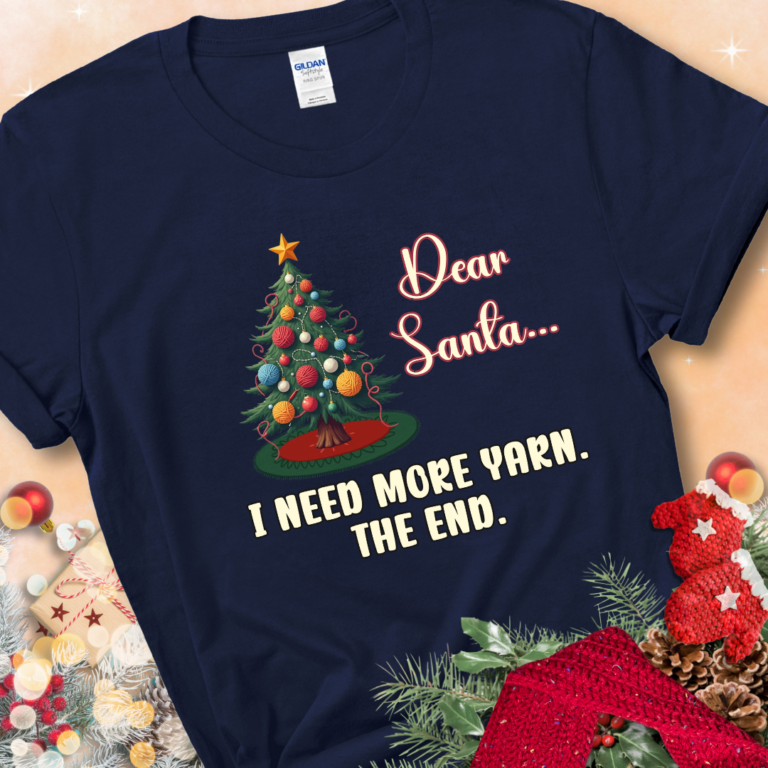 Navy t-shirt with a Christmas tree decorated with yarn-ball ornaments and the stitched message “Dear Santa… I Need More Yarn. The End.”