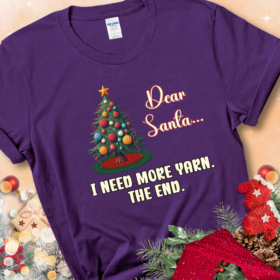 Purple t-shirt with a Christmas tree decorated with yarn-ball ornaments and the stitched message “Dear Santa… I Need More Yarn. The End.”
