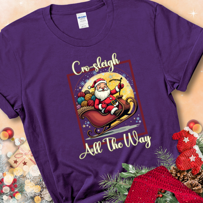 Purple t-shirt with Santa riding in a sleigh overflowing with colorful yarn and the phrase “Cro-Sleigh All The Way.”