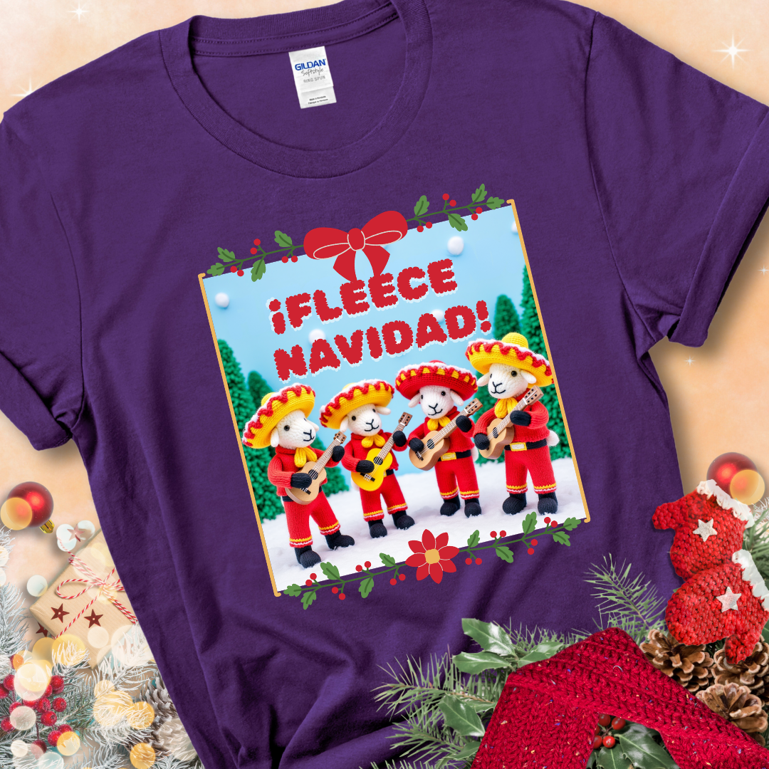 Purple t-shirt with four crocheted sheep in red mariachi outfits holding guitars, standing in a snowy scene under the phrase “¡Fleece Navidad!”