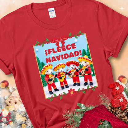 Red t-shirt with four crocheted sheep in red mariachi outfits holding guitars, standing in a snowy scene under the phrase “¡Fleece Navidad!”