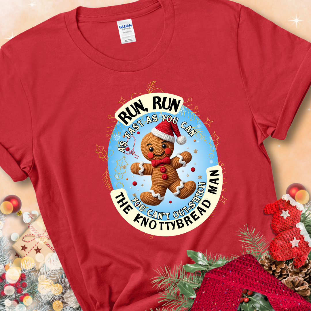 Red t-shirt with a crocheted gingerbread man in a Santa hat and the phrase “You Can’t Out-Stitch the Knottybread Man.”