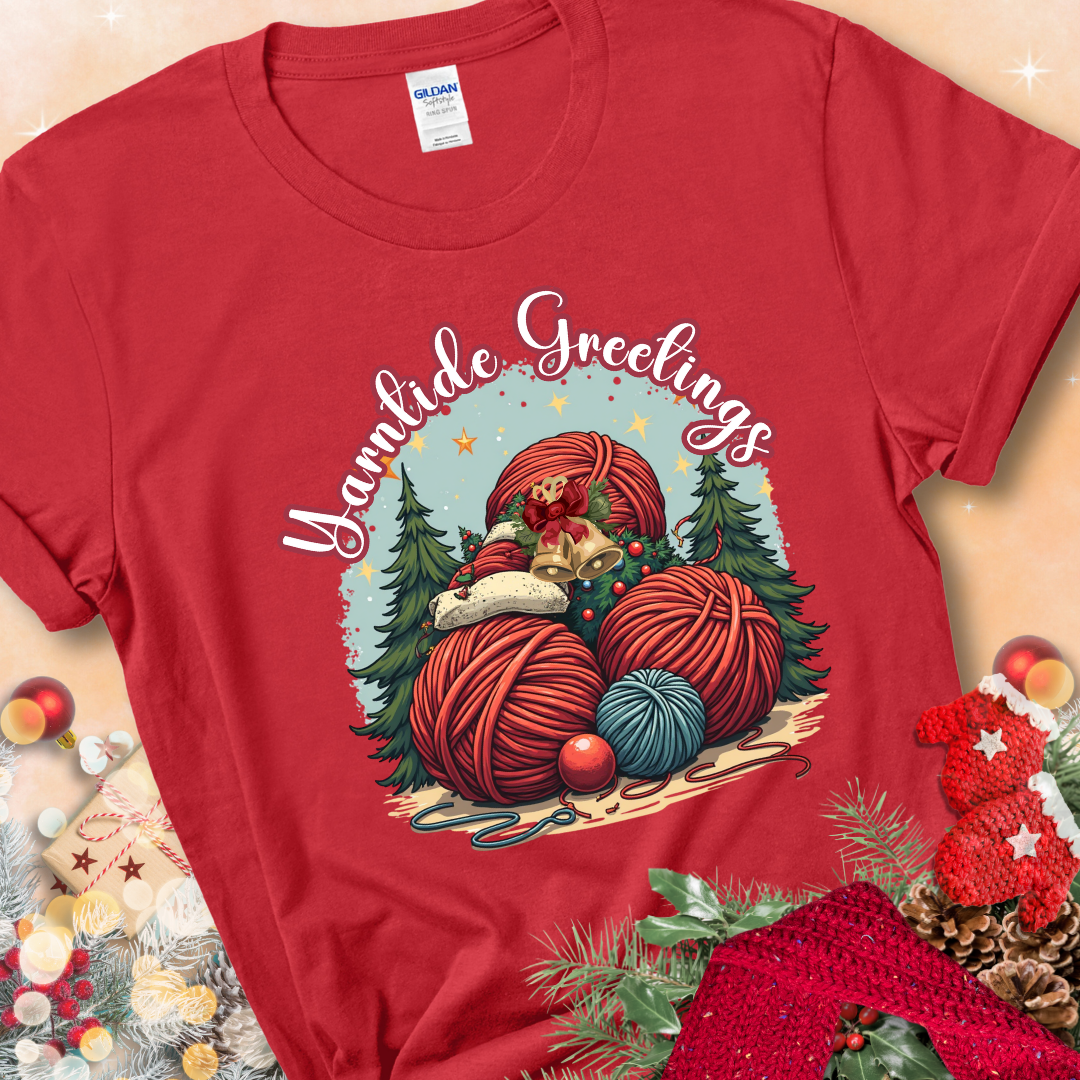 Red t-shirt with red yarn balls, holiday greenery, bells, and the phrase “Yarntide Greetings.”