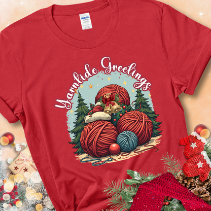 Red t-shirt with red yarn balls, holiday greenery, bells, and the phrase “Yarntide Greetings.”