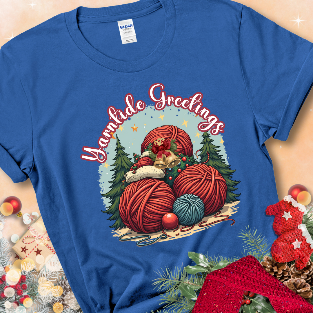 Royal t-shirt with red yarn balls, holiday greenery, bells, and the phrase “Yarntide Greetings.”