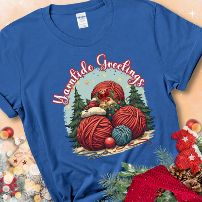 Royal t-shirt with red yarn balls, holiday greenery, bells, and the phrase “Yarntide Greetings.”