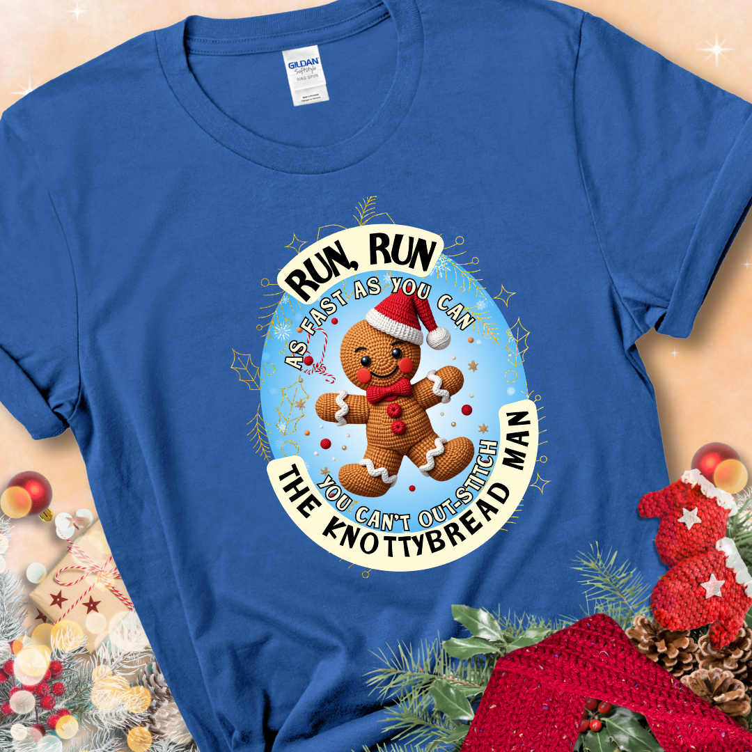 Royal Blue t-shirt with a crocheted gingerbread man in a Santa hat and the phrase “You Can’t Out-Stitch the Knottybread Man.”