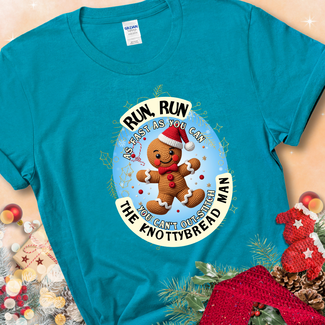 Tropical Blue t-shirt with a crocheted gingerbread man in a Santa hat and the phrase “You Can’t Out-Stitch the Knottybread Man.”