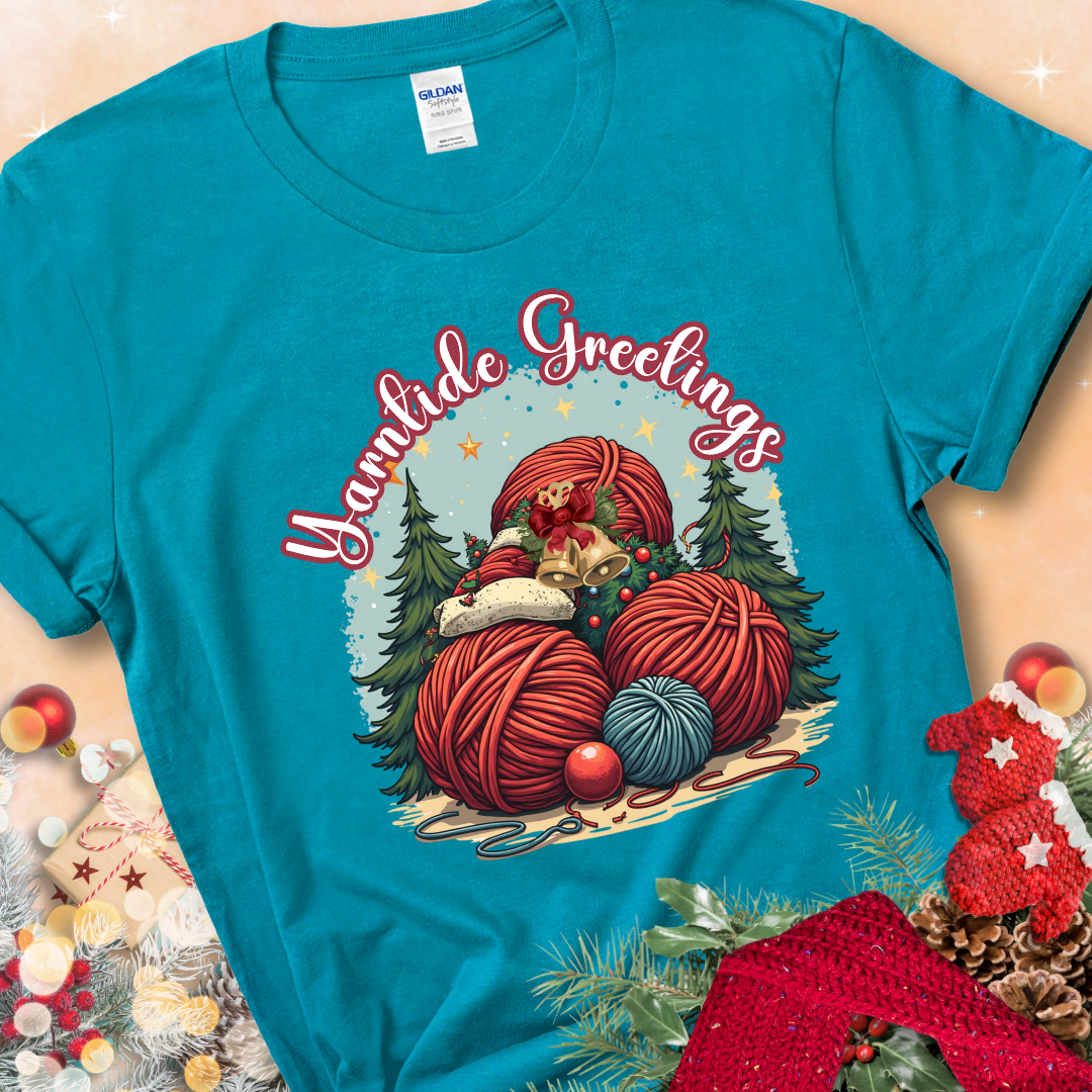 Tropical Blue t-shirt with red yarn balls, holiday greenery, bells, and the phrase “Yarntide Greetings.”
