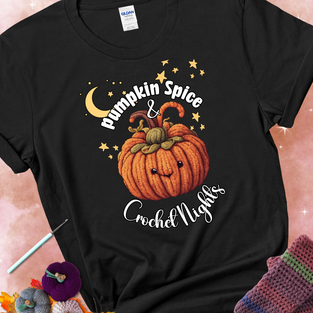 Black t-shirt with a smiling pumpkin crocheted with yarn texture, surrounded by stars and a crescent moon. Text reads “Pumpkin Spice & Crochet Nights.”