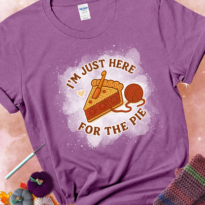 Heather Radiant Orchid t-shirt with a stitched slice of cherry pie with yarn-inspired filling and the phrase “I’m Just Here for the Pie” in red, beige, and cream.