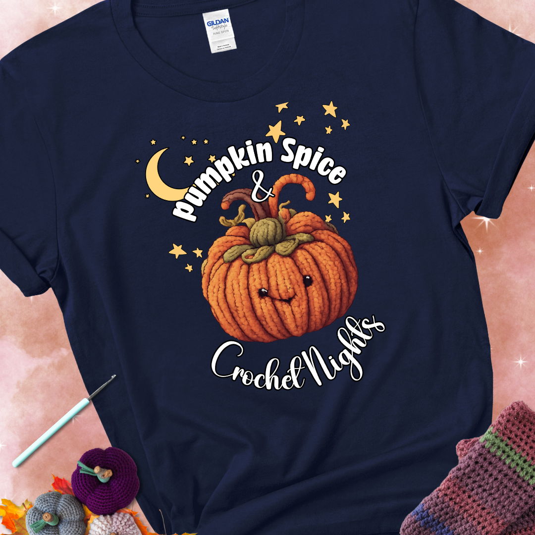 Navy blue t-shirt with a smiling pumpkin crocheted with yarn texture, surrounded by stars and a crescent moon. Text reads “Pumpkin Spice & Crochet Nights.”