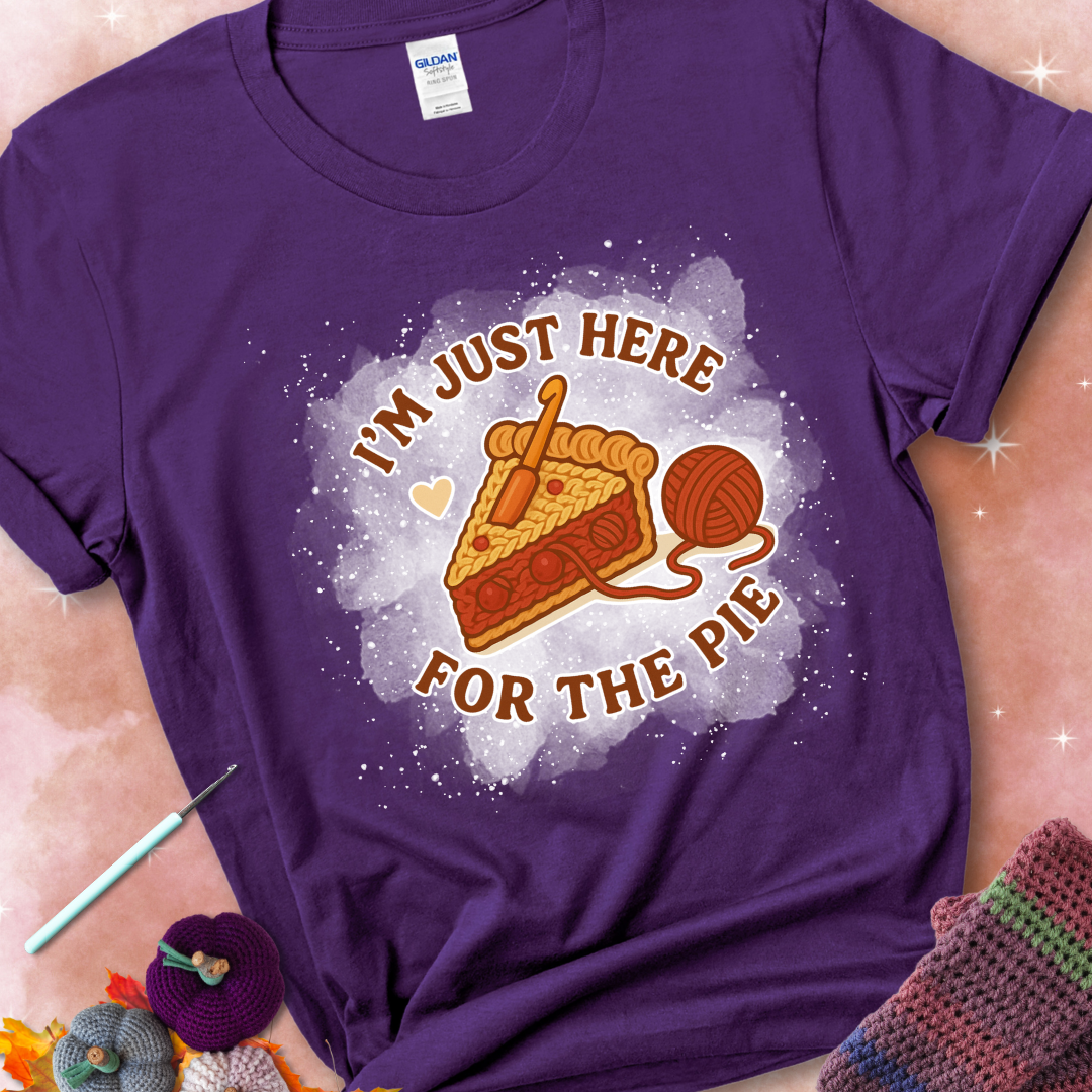 Purple t-shirt with a stitched slice of cherry pie with yarn-inspired filling and the phrase “I’m Just Here for the Pie” in red, beige, and cream.