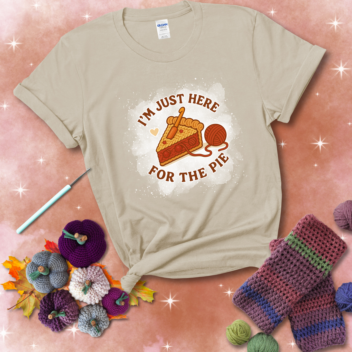 A slice of cherry pie with a crochet hook tucked in the filling and yarn trailing out, blending baking with crochet fun, showing a beige tee with a festive Fall background