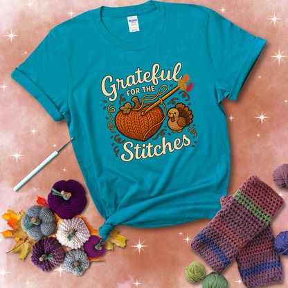 A cozy fall scene with a crochet hook stitching a heart-shaped pumpkin, surrounded by yarn and a small turkey, showing a blue-green tee with a festive Fall background