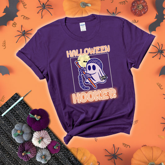 Cartoon ghost crocheter with a yarn ball head, crochet hook, bats, and text “Halloween Hooker,” a fun spooky tee for yarn lovers showing a purple tee with a festive Halloween background