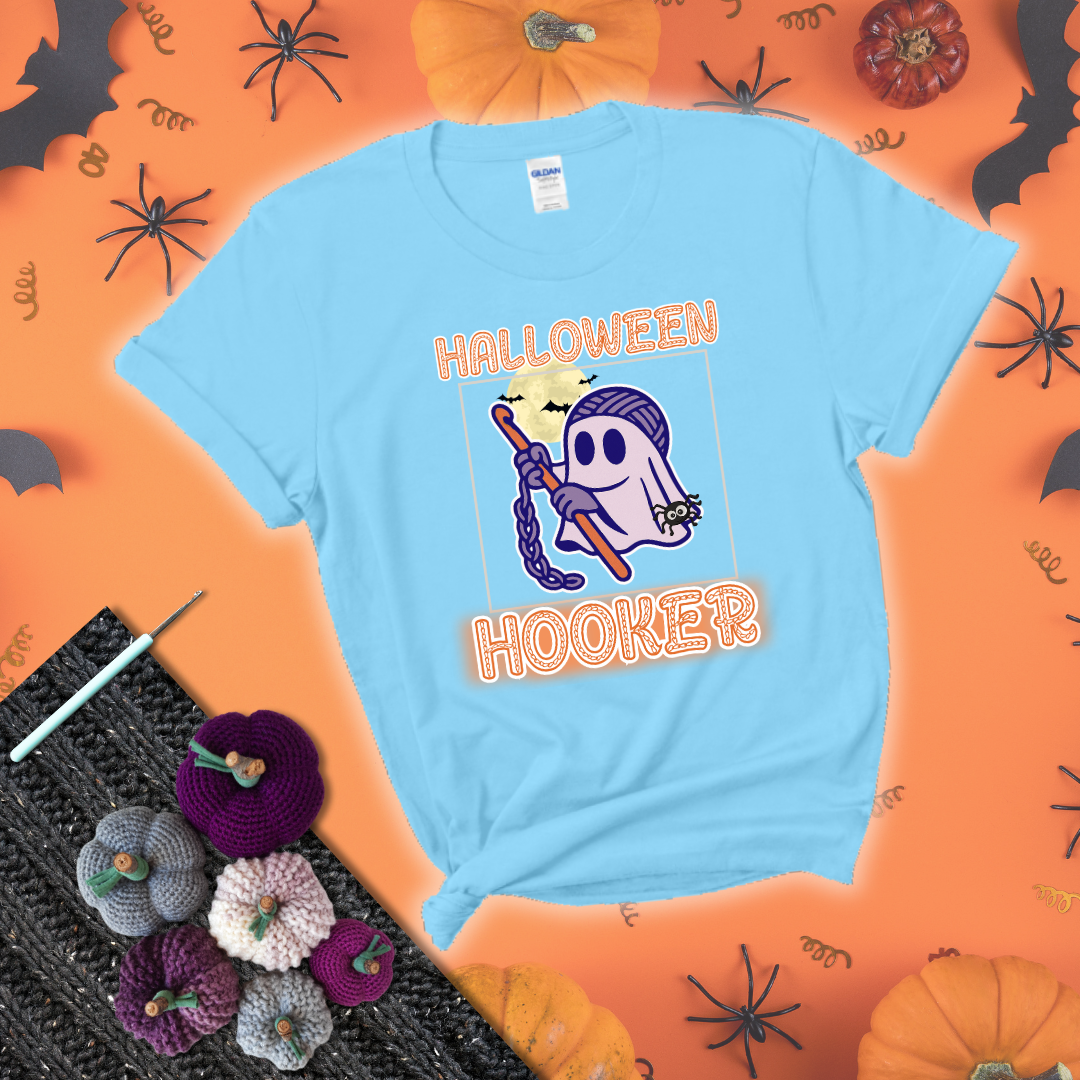 Cartoon ghost crocheter with a yarn ball head, crochet hook, bats, and text “Halloween Hooker,” a fun spooky tee for yarn lovers showing a light blue tee with a festive Halloween background