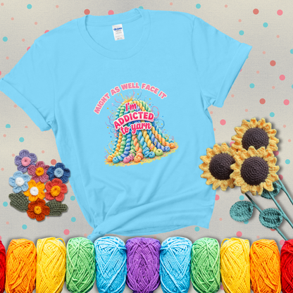 Colorful mountain of pastel yarn hanks with the phrase “Might as well face it, I’m addicted to yarn” in playful pink and red lettering showing a light blue tee with grey sunflower background