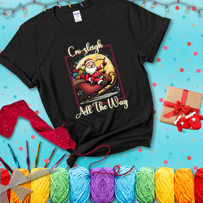 Jolly Santa rides a sleigh overflowing with colorful yarn balls, surrounded by sparkles and holiday cheer. Text reads “Cro-sleigh All the Way" showing a black tee with a festive Christmas background