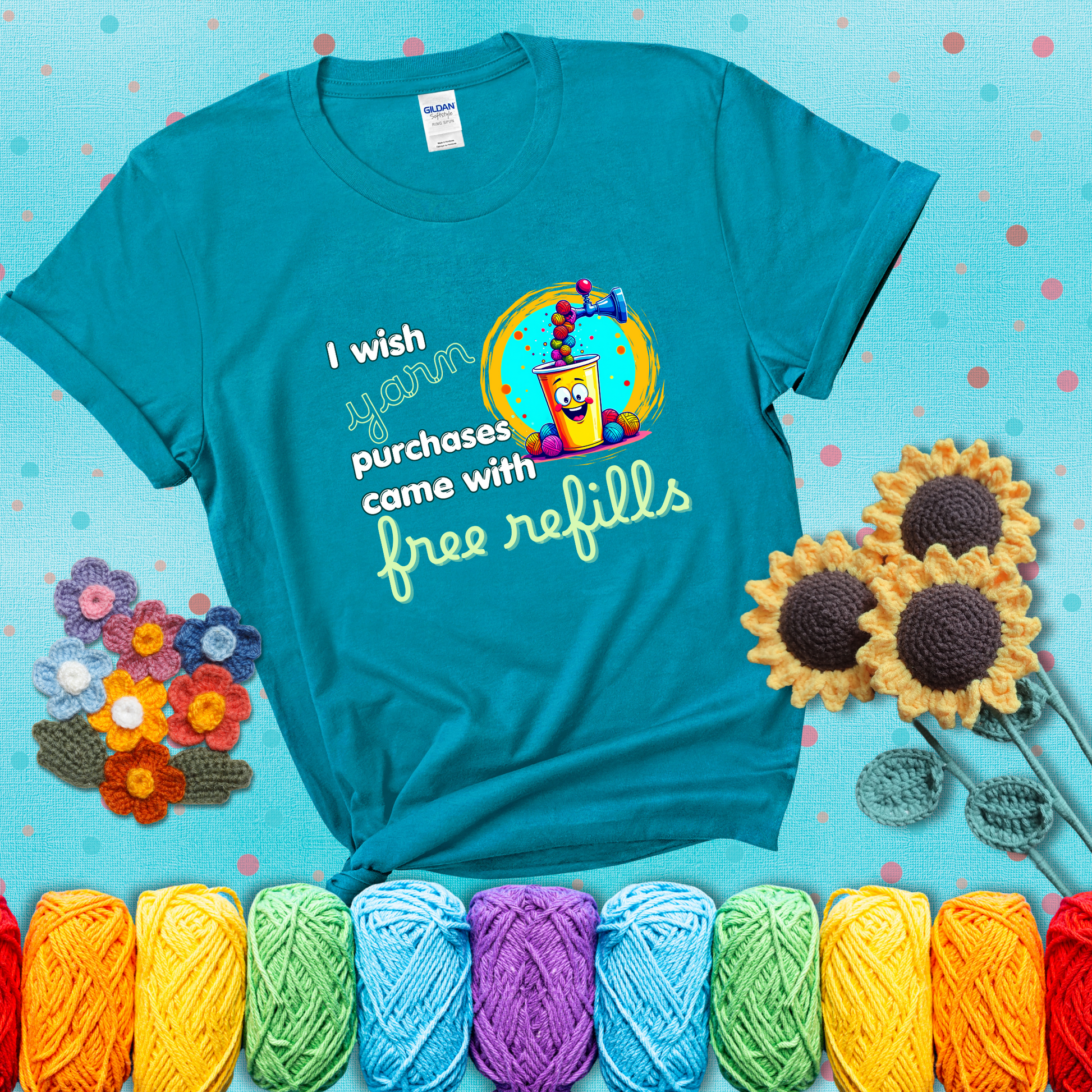 A bright yellow cup with a smiling face is being filled with colorful yarn balls from a soda machine, with the phrase “I wish yarn purchases came with free refills,” showing a blue-green tee with a teal sunflower background