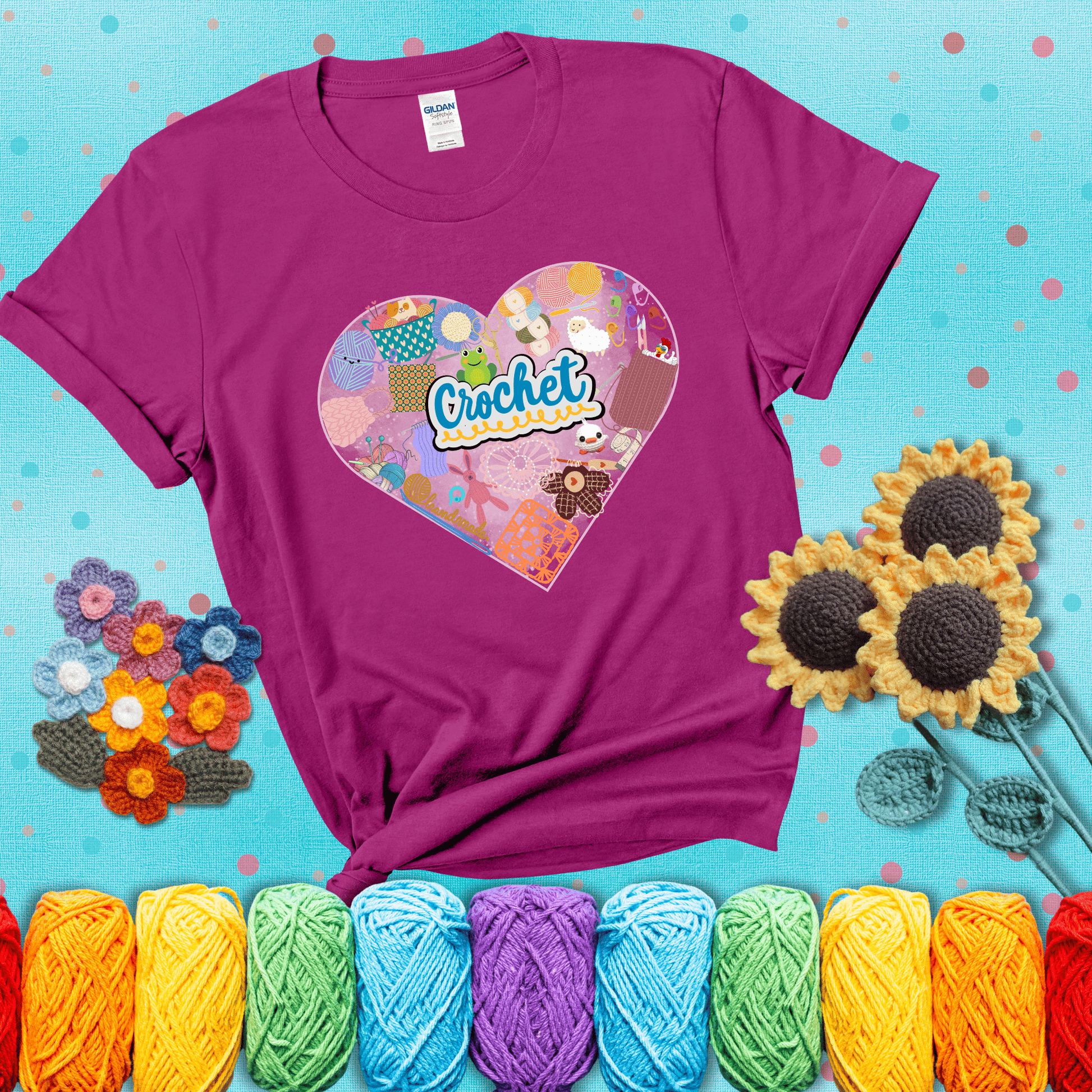 A heart filled with colorful crochet essentials including yarn, hooks, scissors, notions, and handmade items, with the word "Crochet" prominently in the center, showing a magenta tee with a teal sunflower background