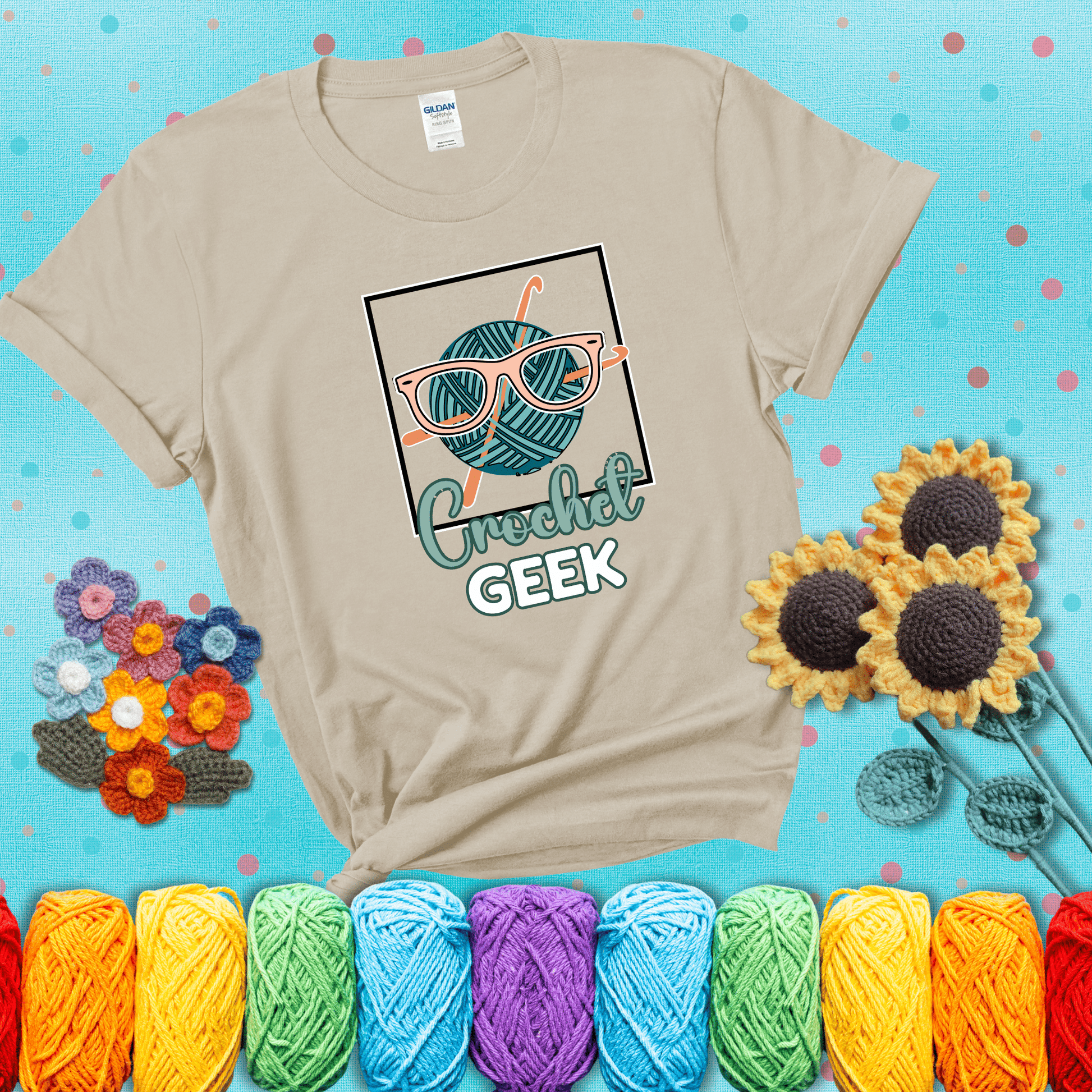 A teal yarn ball with crisscrossed hooks wears oversized nerdy glasses with the phrase “Crochet Geek” in bold, fun text below, showing a beige tee with a teal sunflower background
