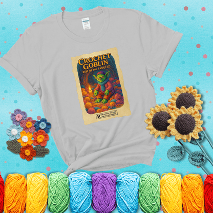 Crochet goblin surrounded by chaotic yarn stash in a cave-like lair. Text reads: “Crochet Goblin: Rise of the Tangled.” A funny fantasy-style tee for yarn hoarders and goblin-mode crafters. showing a light grey tee with a teal sunflower background