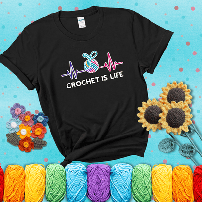 A heartbeat line with a colorful yarn ball and crochet hook in the center, with the words “Crochet is Life”, showing a black tee with a teal sunflower background