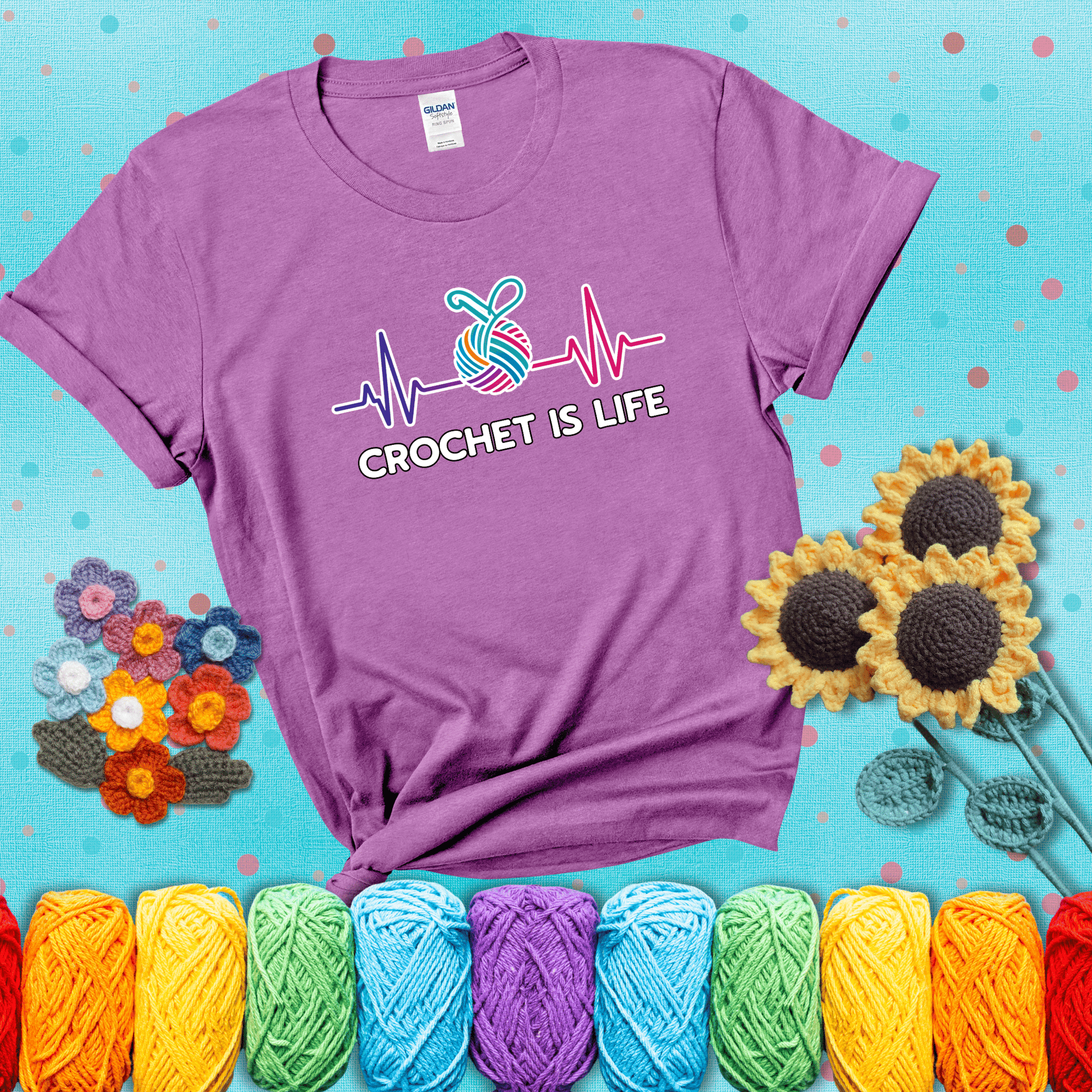 A heartbeat line with a colorful yarn ball and crochet hook in the center, with the words “Crochet is Life”, showing a light purple tee with a teal sunflower background