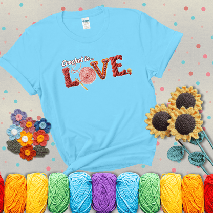 The word "LOVE" spelled with different crochet textures and yarn in red tones, with the phrase “Crochet is…” above in script. showing a light grey tee with a teal sunflower background