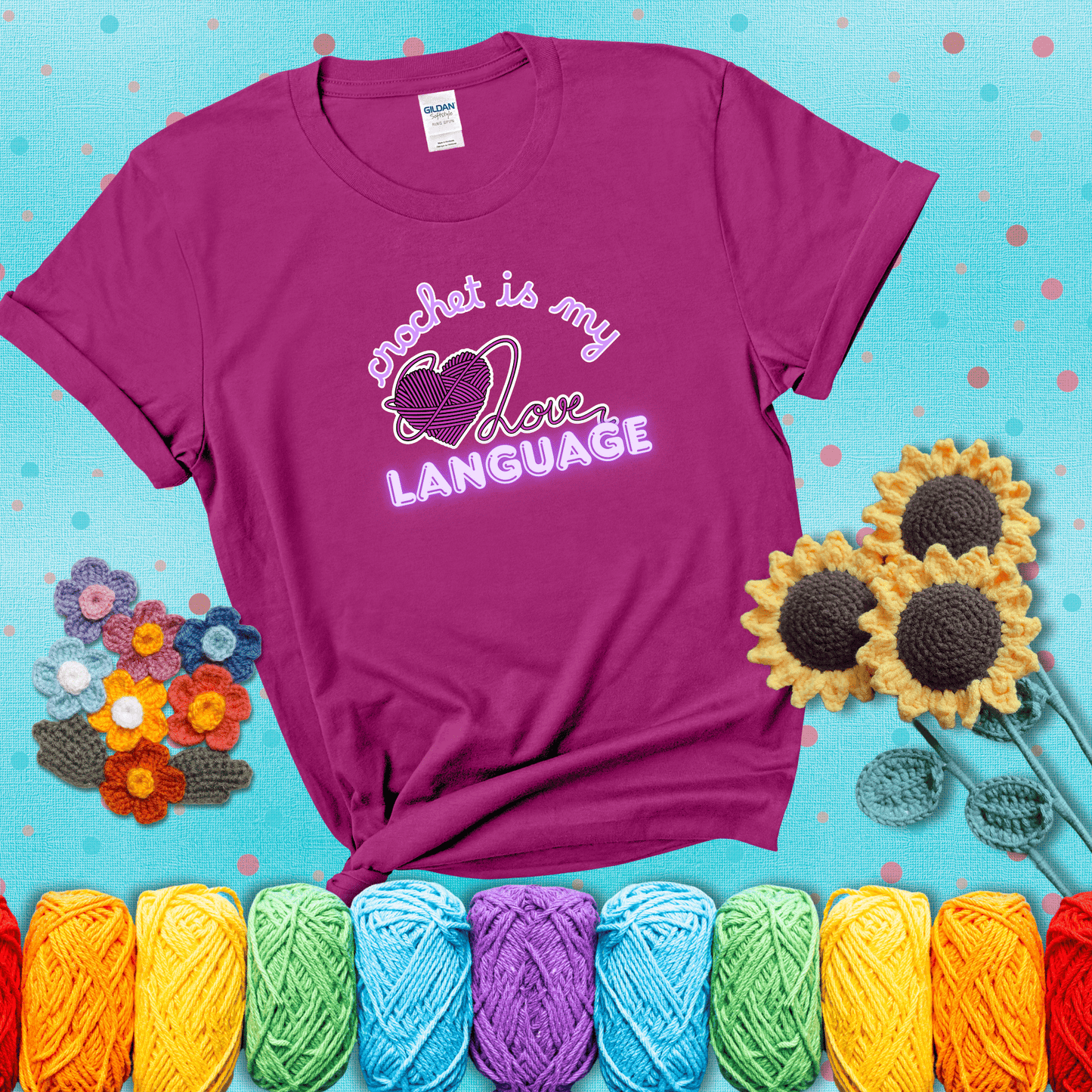 Say it with stitches Design reads 'Crochet Is My Love Language', perfect crochet gift for yarn lovers; showing a magenta tee with a teal sunflower background